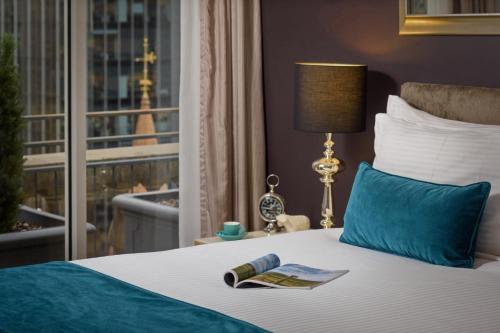 a hotel room with a bed with a book and a window at Treasury on Collins Apartment Hotel in Melbourne