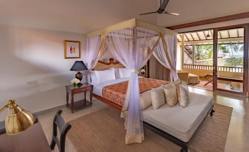a bedroom with a canopy bed and a couch at Taru Villas The Long House - Bentota in Bentota