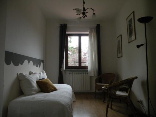 a bedroom with a bed and a window and a chair at Tetto Nuovo B&B in Cuneo