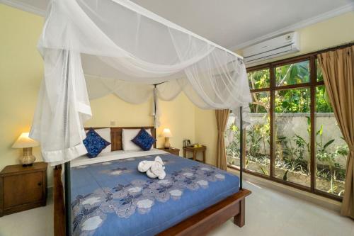 a bedroom with a canopy bed with a stuffed animal on it at Metteyya Healing House in Ubud