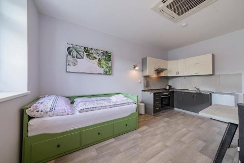 a small bedroom with a green bed and a kitchen at Slovanský penzion in Mikulčice