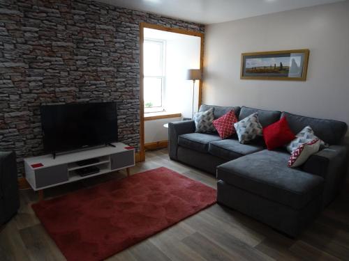 sala de estar con sofá y TV de pantalla plana en The Old Endie Hoose Kirkwall Orkney, en Kirkwall