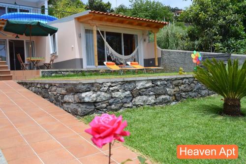 a house with a stone wall and two chairs in the yard at Villa Henriques in Funchal