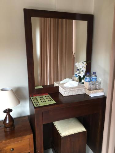a vanity with a mirror and a table with a lamp at Rama House in Ubud