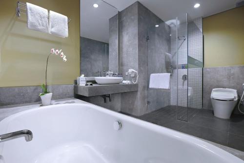 ein Bad mit einer Badewanne, einem Waschbecken und einer Dusche in der Unterkunft ASTON Inn Mataram in Mataram