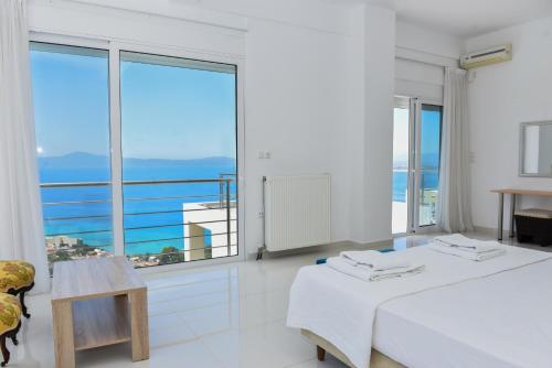 a white room with two beds and a large window at Verga Villas Resort in Kalamata