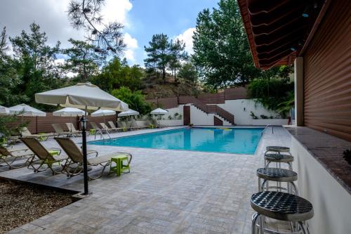 una piscina con sillas y sombrillas junto a una piscina en Platres Valley Houses en Platres