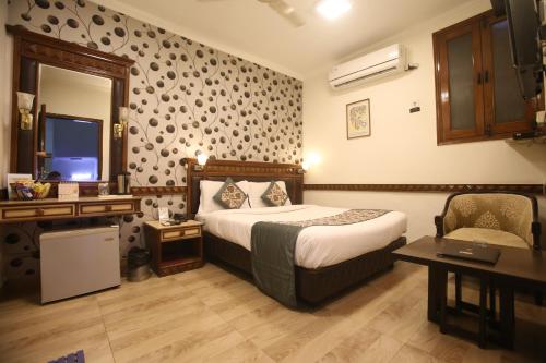 a hotel room with a bed and a desk and a mirror at Hotel Amar Inn- Lajpat Nagar Central Market in New Delhi