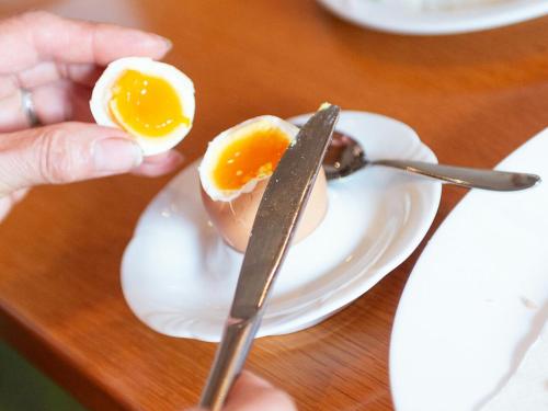 a person cutting an egg on a plate with a knife at Gästehaus Nora in Stein bei Loipersdof