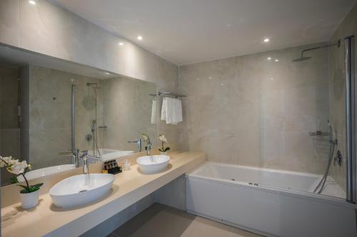 a bathroom with two sinks and a bath tub at Constantinos the Great Beach Hotel in Protaras
