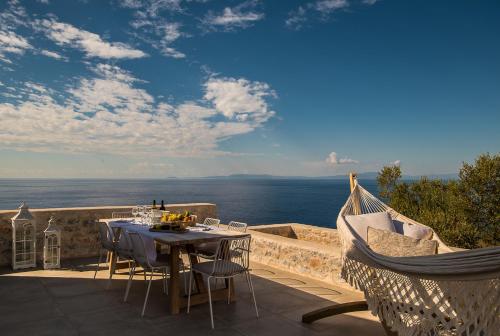 a table and chairs on a balcony with the ocean at BASSA MAINA Villas & Suites in Areopolis