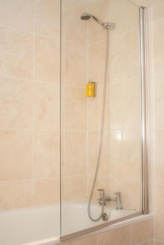 a shower with a glass door next to a tub at Edinburgh House Hotel in Edinburgh