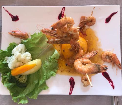 a plate of food with shrimp and vegetables on it at Domus Hotel & Apartments in Shëngjin
