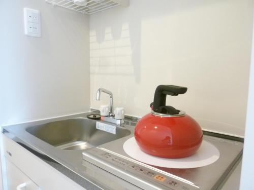 a red tea kettle sitting on top of a kitchen counter at Nagoya Motoyama House A in Nagoya