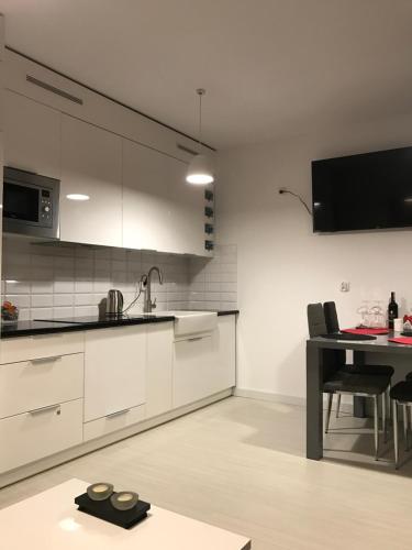 a kitchen with white cabinets and a dining table at Apartament Kilfowa 15/8 in Mechelinki