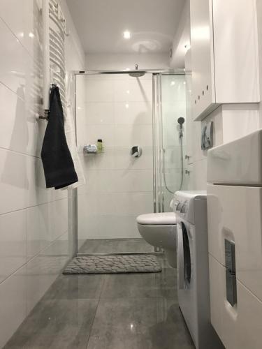 een witte badkamer met een douche en een toilet bij Apartament Kilfowa 15/8 in Mechelinki