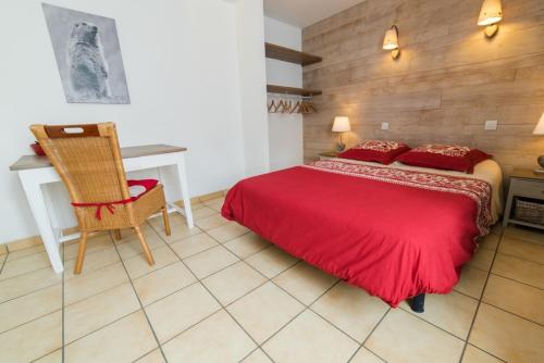 a bedroom with a red bed and a desk at Gîte La Maisonnée in Sazos