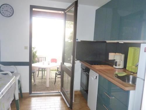 une cuisine avec une porte coulissante en verre menant à une terrasse. dans l'établissement Pavillon T3, 2 terrasses, Narbonne Plage, à Narbonne-Plage