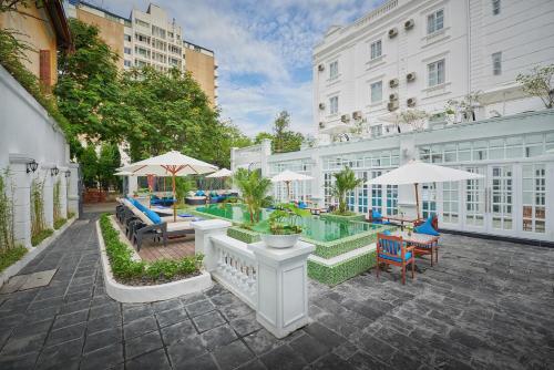 a hotel patio with a pool and chairs and umbrellas at Manoir Des Arts Hotel in Hai Phong