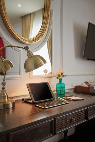 a laptop computer sitting on a desk with a lamp at Manoir Des Arts Hotel in Hai Phong