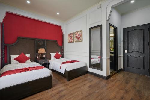 a bedroom with two beds and a red wall at Manoir Des Arts Hotel in Hai Phong