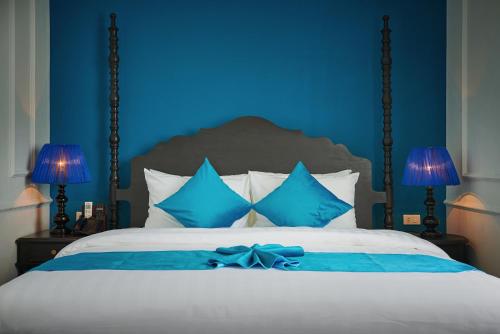a blue bedroom with a bed with a bow on it at Manoir Des Arts Hotel in Hai Phong