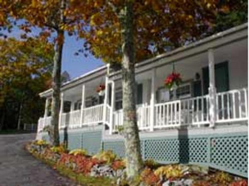 a white house with trees in front of it at Mount Battie Inn in Lincolnville