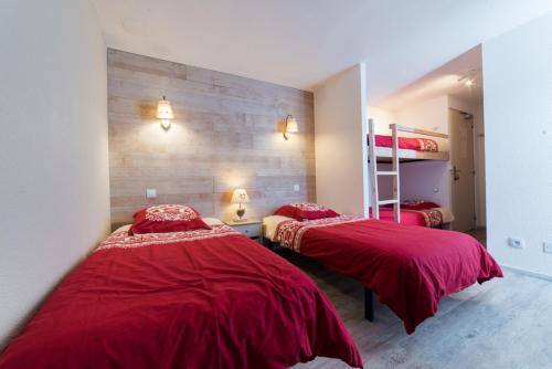 two beds in a room with red comforter at Gîte La Maisonnée in Sazos
