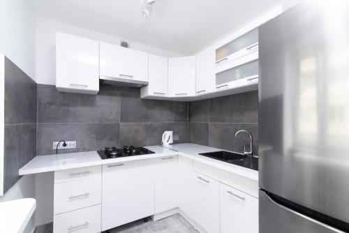 La cuisine est équipée de placards blancs et d'un réfrigérateur en acier inoxydable. dans l'établissement Pańska Residence, à Varsovie