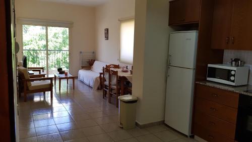 uma cozinha e sala de estar com um frigorífico e uma mesa em Lazaros Pissouri Apartments em Pissouri