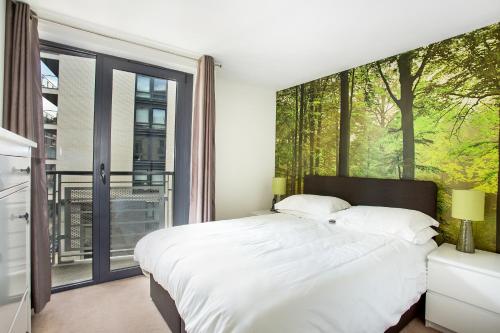 a bedroom with a white bed and a large window at Beautiful, Secure, 2-bedroom Canal-side Apartment in London
