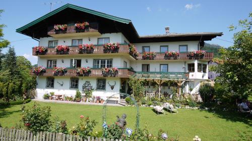 a large white house with flowers on the balcony at Frühstückspension Huber in Fuschl am See