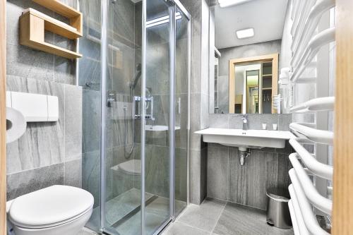 a bathroom with a shower and a toilet and a sink at Villa Ozone in Sopot