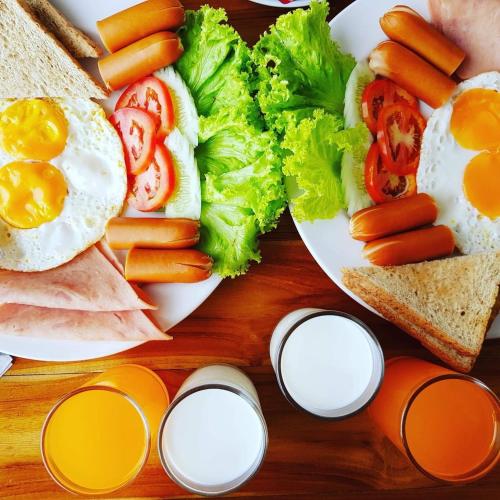 Una mesa cubierta con platos de comida con huevos y verduras. en Charming Lipe Beach Resort, en Ko Lipe