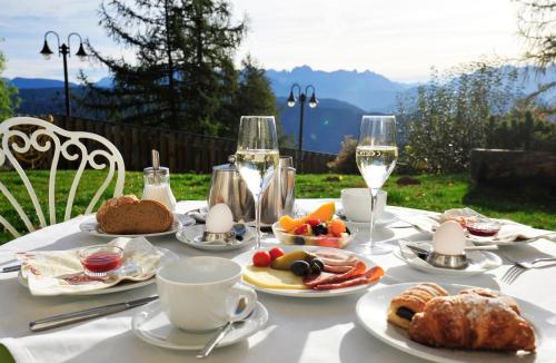 einen Tisch mit Teller mit Speisen und Gläsern Wein in der Unterkunft Hotel König Laurin in Jenesien