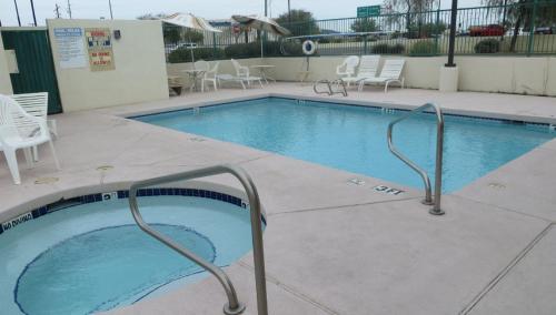 a large swimming pool with white chairs around it at Days Inn by Wyndham Phoenix North in Phoenix