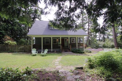 a small green house with two chairs in the yard at Shore Thing Retreat in Eastsound