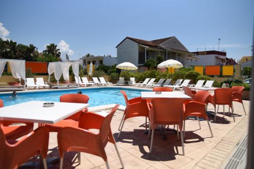 a row of tables and chairs next to a swimming pool at Kavos Central gardens in Kavos