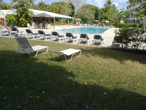 a pool with lounge chairs and a table in the grass at Condominium 220 in Saint James