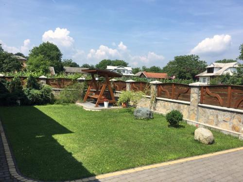 un patio con una valla de piedra y un jardín con césped en Vacation home en Yabluniv