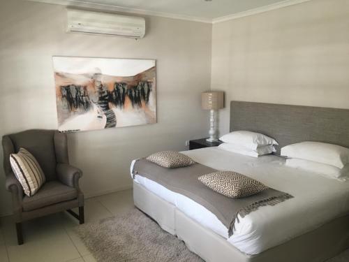 a bedroom with a large bed and a chair at Barra Beach Villa in Inhambane