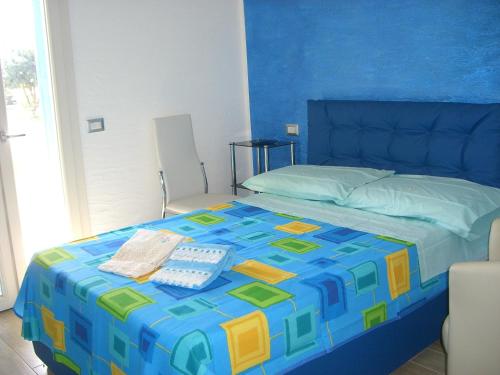 um quarto com uma cama com uma colcha azul e amarela em S'Olivariu Village Affittacamere em Piscinas