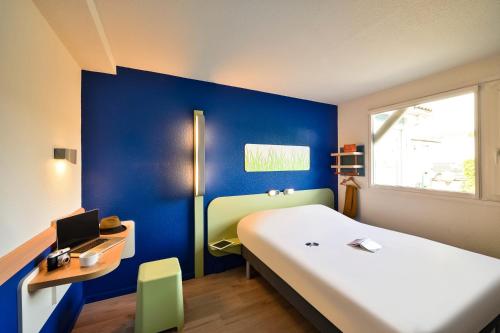 um quarto com uma cama branca e uma parede azul em Ibis budget Chambéry Centre Ville em Chambéry