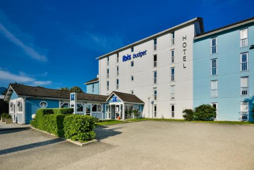 a large white hotel building with a parking lot at Ibis budget Chambéry Centre Ville in Chambéry