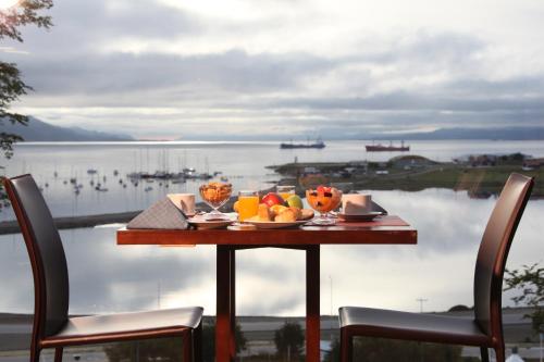 a table with fruit on it with a view of the water at Hotel Las Lengas in Ushuaia