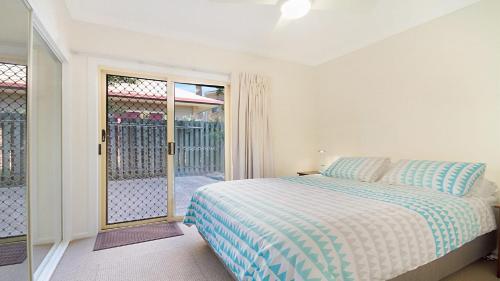 a bedroom with a bed and a sliding glass door at Orient Lane on the Hill by Kingscliff Accommodation in Kingscliff