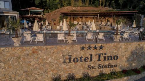 a hotel sign with chairs and umbrellas and a pool at Hotel & Spa Tino Sveti Stefan in Ohrid