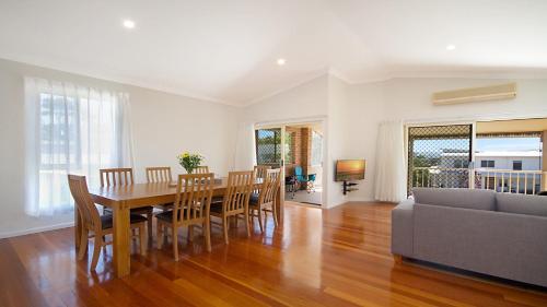 a dining room with a table and chairs and a couch at Orient Lane on the Hill by Kingscliff Accommodation in Kingscliff