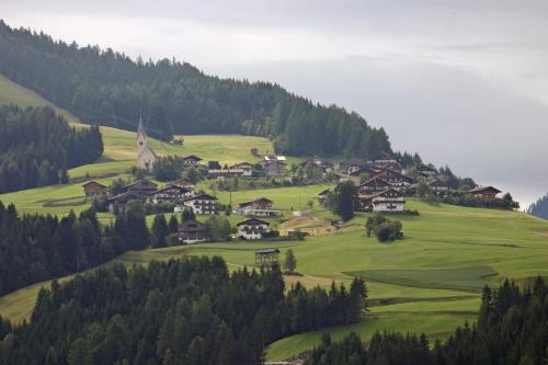a small village on a green hill with a church at Gästehaus Maria in Kartitsch