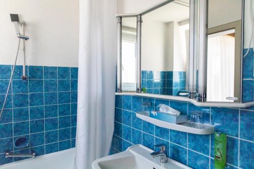 a blue tiled bathroom with a sink and a mirror at Hotel JÄGERHAUS in Singen am Hohentwiel in Singen